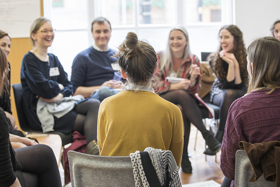 People sitting on chairs in a circling and laughing, during an earlier open space event we facilitated